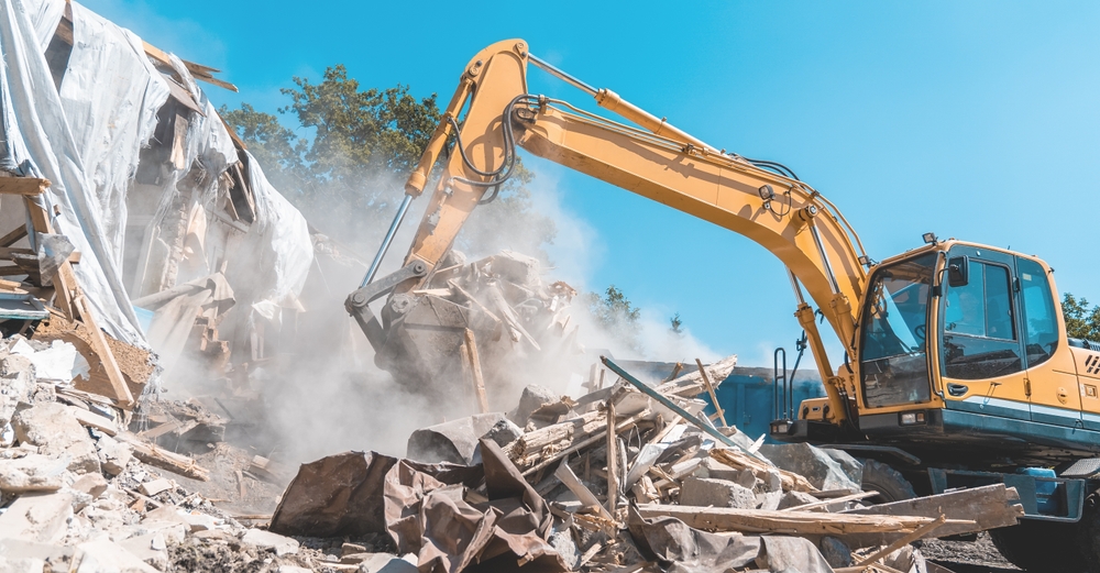a yellow excavator with a pile of debris representing skip bin hire.